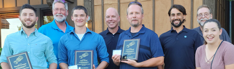 group of seven male and one female GE Vernova employees, three of the men are holding appenticeship certificate cards and plaques